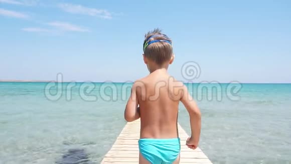 快乐的小男孩跑进大海享受暑假清澈的蓝色水金色的沙滩视频的预览图