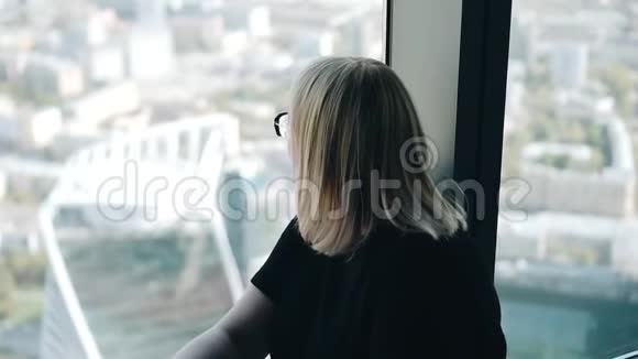 女孩坐在一栋高层建筑的窗户边的地板上视频的预览图