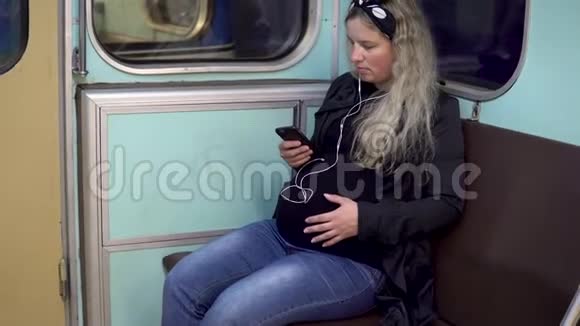 一位孕妇正在地铁列车上用耳机听音乐旧地铁列车视频的预览图