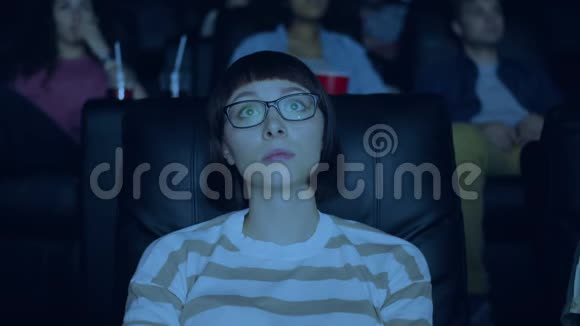 女学生在电影院看悲伤剧摸脸看屏幕视频的预览图