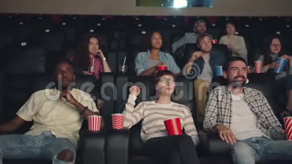 快乐的千禧一代在电影院里笑着看有趣的电影视频的预览图