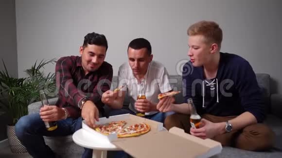 三个快乐的年轻人吃披萨从桌子上拿走视频的预览图