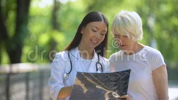 康复中心公园的护士和老年妇女看关节x线视频的预览图