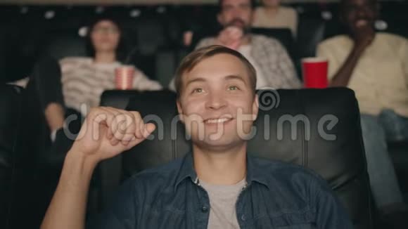 在电影院看电影时吃爆米花喝橙汁的年轻人视频的预览图