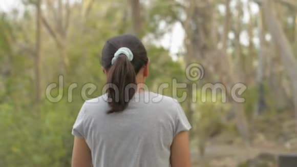 从后面看亚洲女人戴着眼镜穿着休闲服装在自然公园悠闲地散步在夏天视频的预览图