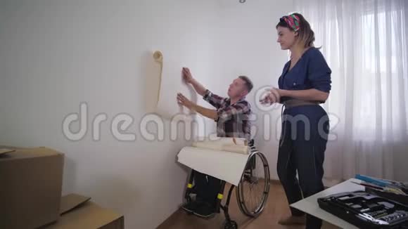 幸福的夫妻残疾人丈夫坐轮椅年轻的妻子在修理时选择漂亮的壁纸视频的预览图