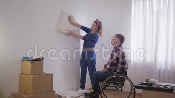 家庭关系心爱的残疾人坐在轮椅上带着关怀微笑的妻子选择新的室内壁纸视频的预览图