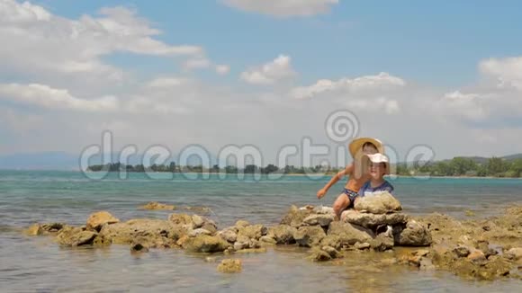 孩子们在玩石头和海水阳光明媚的夏日海滨上的小兄弟两个可爱的男孩在玩游戏视频的预览图