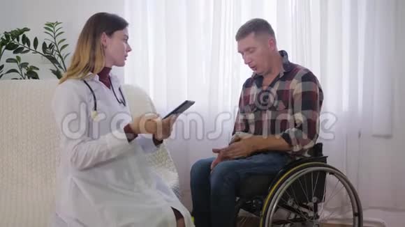 社会工作者残疾男性轮椅上的男子在接受体检时向医护人员讲述他的健康问题视频的预览图