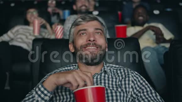 快乐的中年人正笑着在电影院里吃爆米花看电影视频的预览图