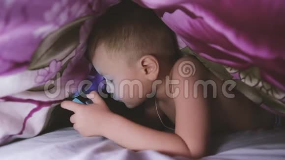 在毯子下面玩智能手机的男孩视频的预览图