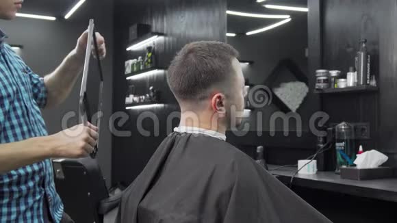 理发师拿着镜子给他的男客户检查新发型视频的预览图