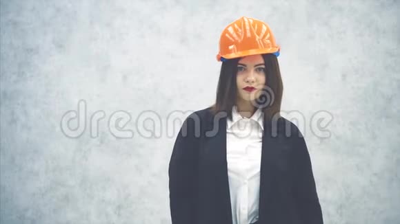漂亮的年轻女建筑师戴着头盔和西装举起一个时钟指着它摆姿势视频的预览图