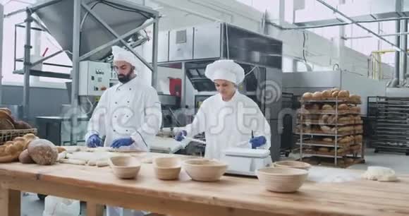 在一家商业烘焙厂工作两个面包师非常有魅力他们制作面团来烘焙面包视频的预览图