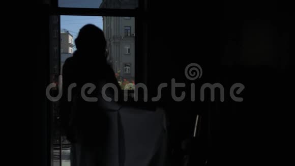 剪影在一个穿丝绸长袍的漂亮女孩的窗前跳舞视频的预览图