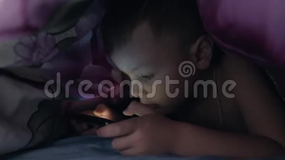 在毯子下面玩智能手机的男孩视频的预览图
