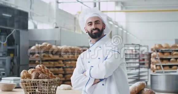 面包业面包师厨师长胡子的人站在他的工作旁边直视着镜头笑容满面视频的预览图