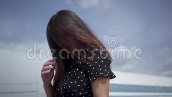 肖像年轻的黑发女孩转身看着镜头前的大白飞机和天空矫直视频的预览图