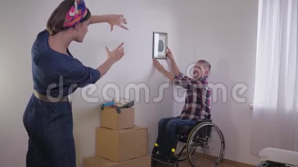 轮椅上的残疾人在妻子用手指做框架时会挂照片然后选择合适的位置视频的预览图