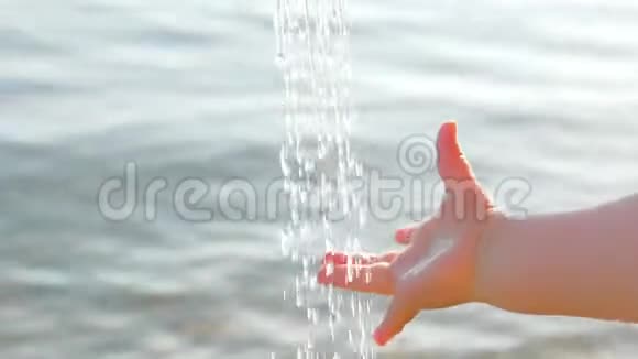 婴儿手抓水滴在海景背景上幼儿用手拿着装有海水的水滴玩视频的预览图