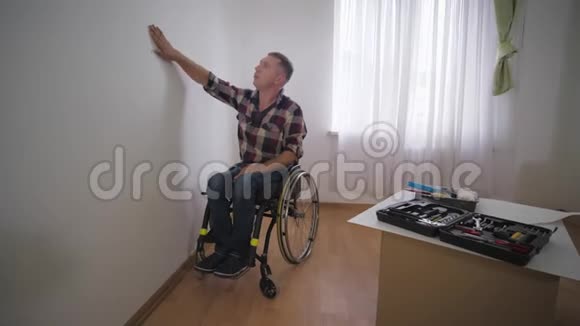 残疾人在轮椅上选择与心爱的儿子在房间里选择壁纸在修理期间选择家庭关系视频的预览图
