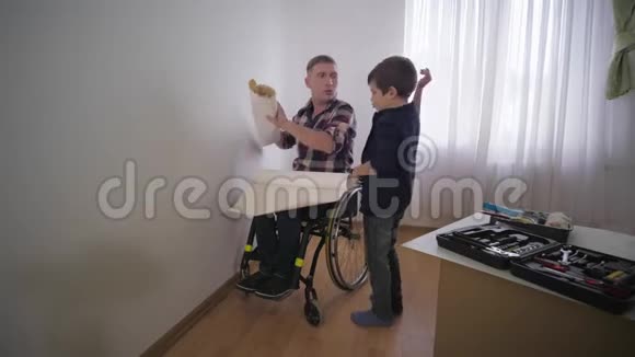 幸福的家庭快乐的小儿子有残疾的父亲和他美丽的母亲在修理期间选择房间里的壁纸视频的预览图