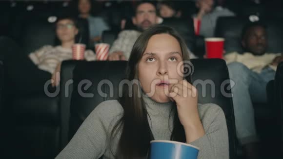 恐怖的女人在电影院看恐怖电影吃着爆米花闭上眼睛视频的预览图