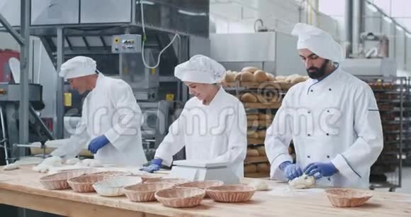 专业面包师在商业厨房行业的一张大桌子上制作面团来烘烤面包视频的预览图