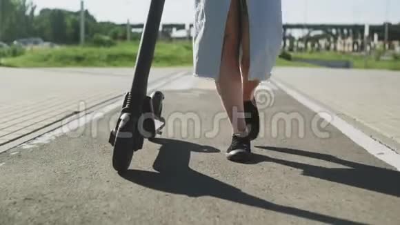 女人带着她的电动滑板车在公园里散步视频的预览图