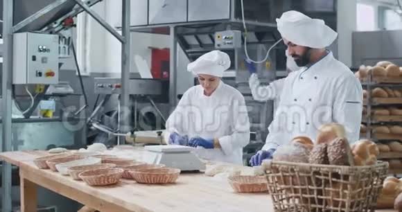 烘焙行业三个专业的面包师他们集中在面团上准备烘焙面包时尚视频的预览图