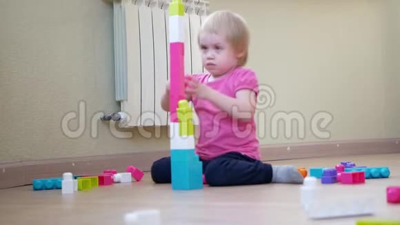 孩子搭建一座彩色积木塔可爱的小女孩在玩五颜六色的建筑塑料块上视频的预览图