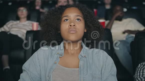 恐怖的非裔美国少女在电影院观看恐怖电影的缓慢动作视频的预览图