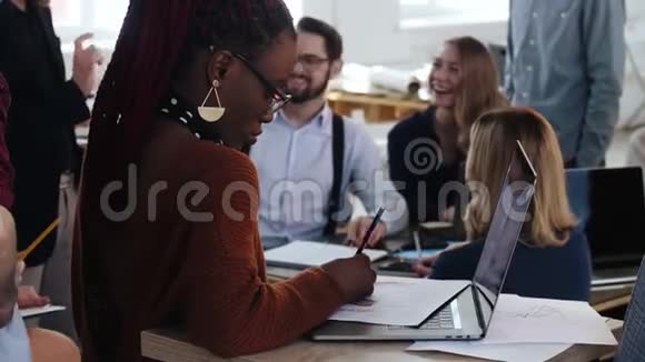 美丽的非洲年轻女性在笔记本电脑上工作快乐的多民族商务人士在办公室背景视频的预览图