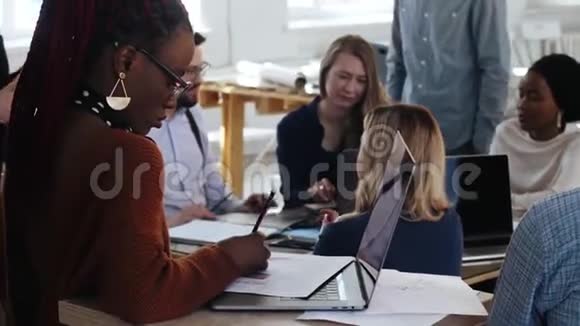 专注的黑人年轻女性工作与笔记本电脑快乐的多民族微笑商务人士合作在现代办公室视频的预览图