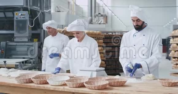 三个有魅力和时尚的面包师女人和男人努力工作面团制作片烘焙面包缓慢的动作视频的预览图
