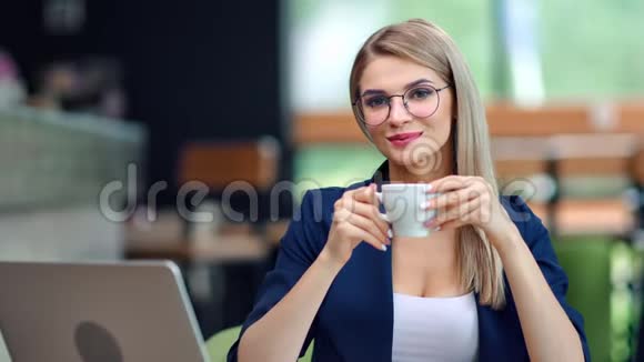 快乐美丽的年轻女商人在餐厅里悠闲地喝咖啡摆姿势看镜头视频的预览图