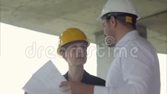 建筑工地上一位男经理戴着安全帽和他的女同事交谈视频的预览图