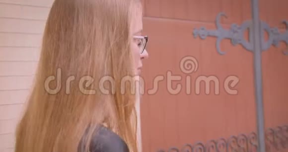年轻漂亮的女性戴着眼镜穿着漂亮的长头发在户外快乐地散步视频的预览图