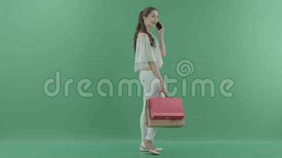 年轻开朗的美女带着袋子在智能手机和绿色屏幕上交谈视频的预览图
