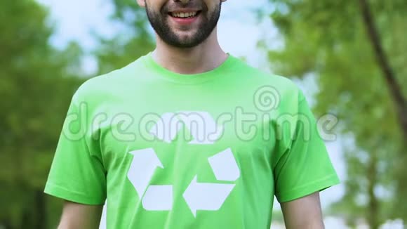 绿色t恤上带回收标志的骄傲男镜头微笑生态视频的预览图