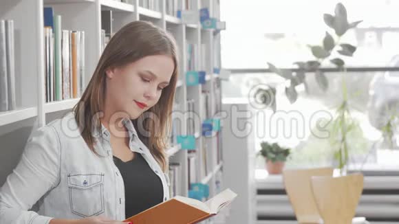 可爱的年轻女子在图书馆看书时对着镜头微笑视频的预览图