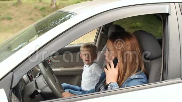 妈妈在车轮后面打电话坐在一个孩子旁边视频的预览图