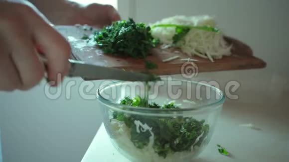 男人用手把切碎的绿色草药放进玻璃碗里视频的预览图