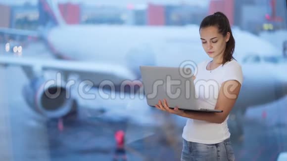 在机场窗户附近工作的女人背景模糊的飞机视频的预览图