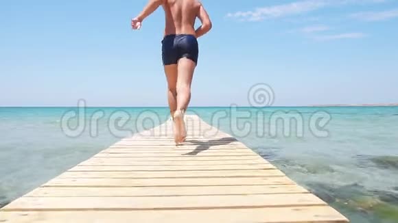暑假快乐青少年跑进大海享受暑假清澈的蓝色水金色的沙滩视频的预览图