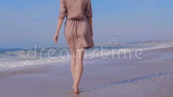 在沙滩上和海浪一起散步的女人视频的预览图
