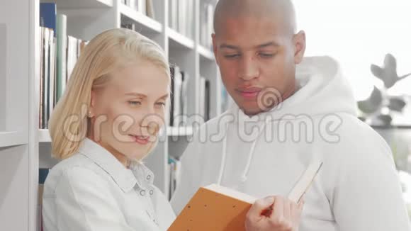 一对快乐的多民族夫妇一边看书一边对着镜头微笑视频的预览图