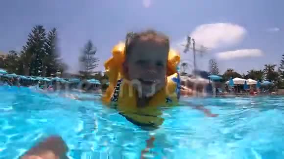 一个穿救生衣的孩子正快乐地在游泳池里游泳视频的预览图
