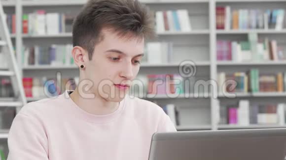 一个年轻的男学生在图书馆对着镜头微笑的被裁剪的镜头视频的预览图