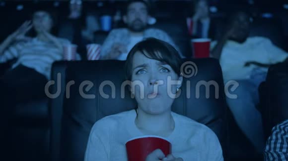 在电影院看悲伤电影和吃爆米花的漂亮女孩慢动作视频的预览图